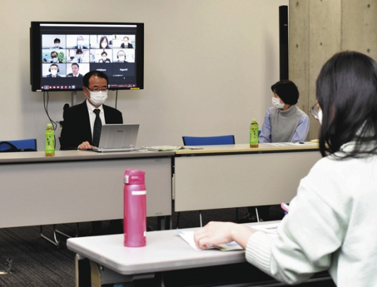 ズームを使いながらメディアリテラシーについて語る鈴木局長（左）＝中村区の愛知大名古屋キャンパスで