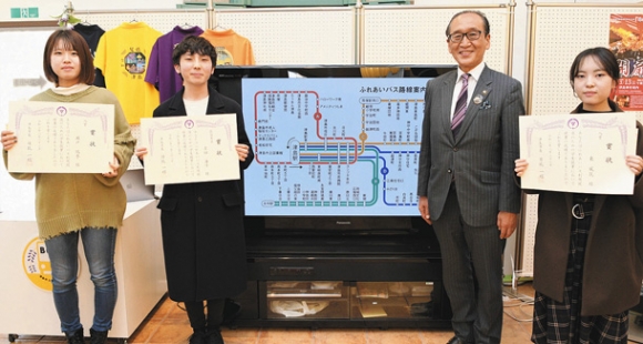 ふれあいバス路線図デザインの優秀作品に選ばれた瀬戸さん（左端）、吉田さん（左から２人目）、東さん（右端）。ディスプレーは吉田さんの作品で、２０２１年度中から使用される＝津島市本町１の市観光交流センターで