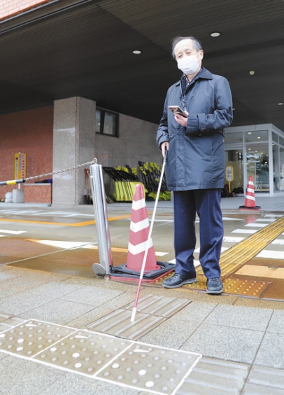 印付きの点字ブロックをスマートフォンのカメラで読み取る米島芳文さん＝金沢市役所で