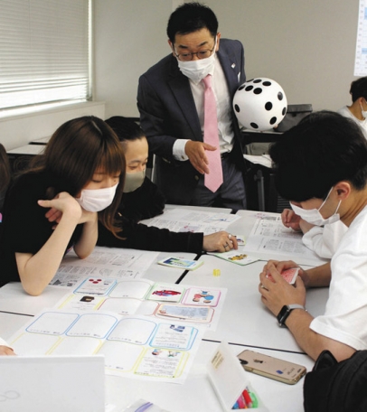 石原さん（中央）からゲーム形式で投資の知識を学ぶ学生たち＝名古屋市昭和区の中京大で