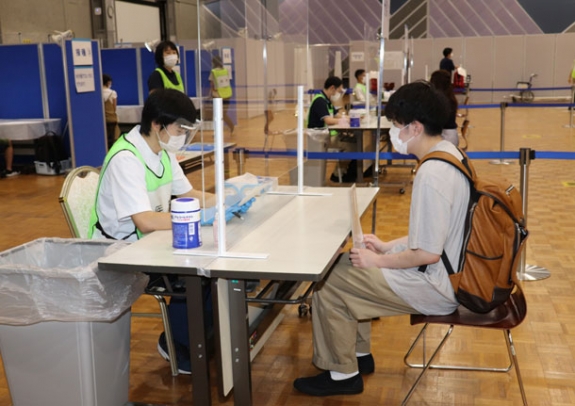 医師（左）から健康状態などを問う予診を受ける学生＝３日、石川県野々市市の金沢工業大で