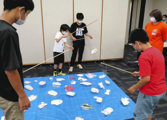 魚釣りゲームを通じ、海や魚を守ることの大切さを学ぶ児童ら＝稲沢市中央図書館で