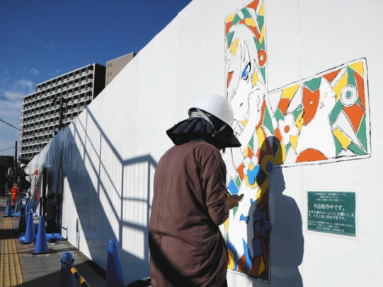 工事現場を囲う壁にイラストを描く学生たち＝北区名城２で