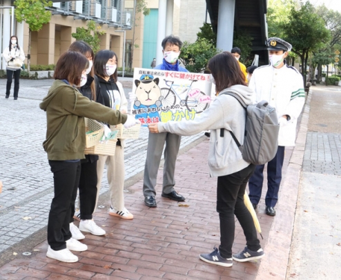 自転車の鍵掛けを呼び掛けて付箋を配布する学生たち＝野々市市扇が丘で