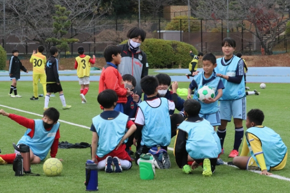 試合の間に作戦を考える児童とコーチの大学生＝日進市岩崎町の愛知学院大日進キャンパスで