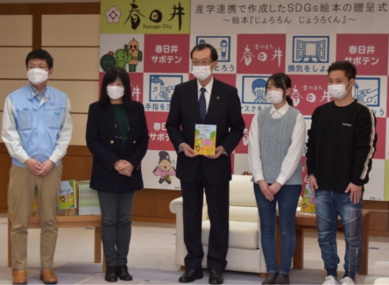 伊藤市長（中）に絵本を手渡した本多社長（左）や中部大の学生ら