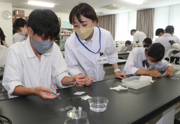 ゼミ生の指導を受けながら実験に取り組む生徒たち＝伊勢市神田久志本町の皇学館大で