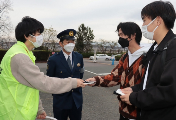 チラシ入りのティッシュなどを渡し自転車盗への注意を呼びかける学生（左）＝春日井市松本町の中部大で