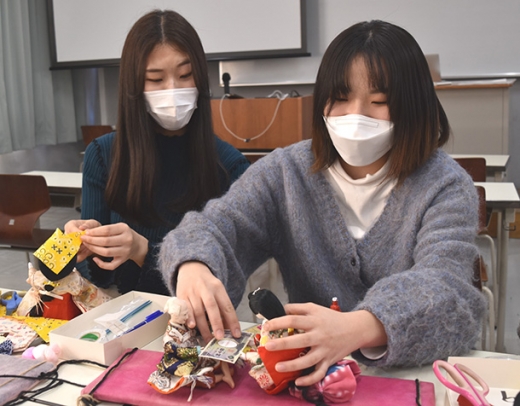 自由な発想でひな人形をリメークする学生たち＝豊明市の名古屋短大で