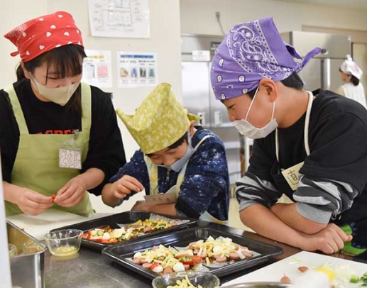 学生のサポートを受けながら楽しそうに料理をする子どもたち＝日進市の愛知学院大で