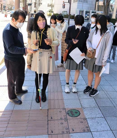 コード化点字ブロックをスマートフォンで読み取る参加者たち＝金沢市南町で