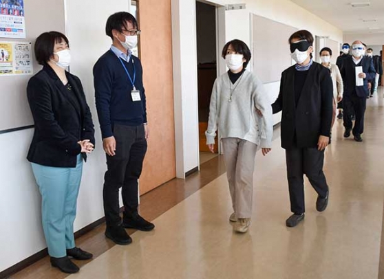 アイマスクを着けた人の誘導を体験する教職員や学生たち＝豊明市の桜花学園大で