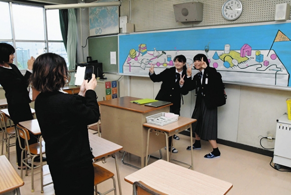 黒板に描かれた作品の前で記念撮影をする新入生ら＝中区の前津中学校で