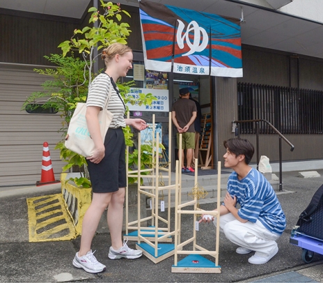 設置した作品を前に交流する学生ら＝津島市橋詰町の池須温泉で