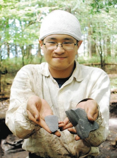 調査で見つかった石片を持つ学生＝下呂市で