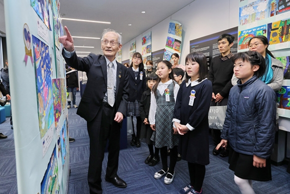 受賞作を飾ったノーベル賞記念展示室で、吉野終身教授（左）の話を聞く受賞した子どもたち＝名古屋市天白区の名城大で
