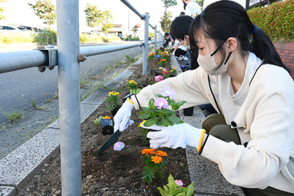 キャンパス前の道路沿いに花を植える学生＝瑞穂市穂積で