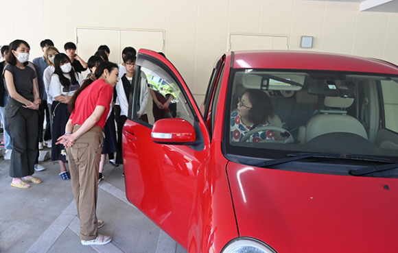 車いすを積んで運転席に乗り込む丹羽さんの様子を見学する学生たち＝長久手市福井の「シンシアの丘」で