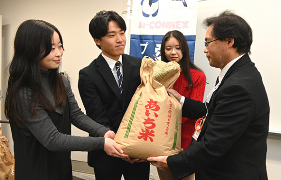 中村区社協の平賀事務局長（右）に米を手渡す愛知大生ら＝名古屋市中村区の愛知大名古屋キャンパスで