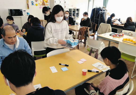 試食会でグラノーラを配る学生（中央）ら＝稲沢市重本の就労継続支援Ｂ型事業所「いちょう」で