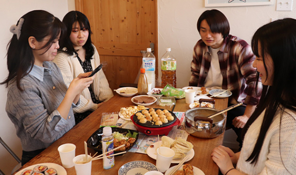 たこ焼きパーティーの様子を撮影する学生ら＝港区のレンタルスペースで