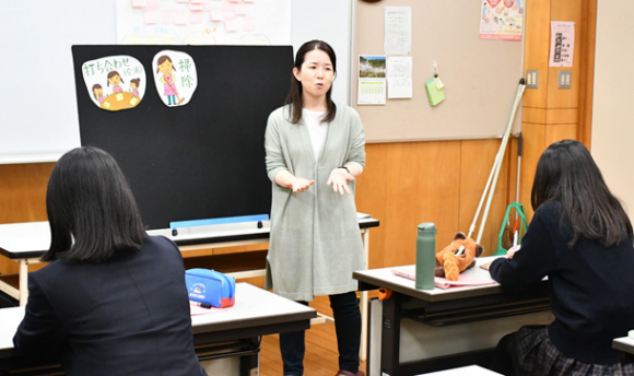 栗岡准教授から保育者の一日の流れを教わる生徒たち=土岐市下石町の土岐紅陵高で