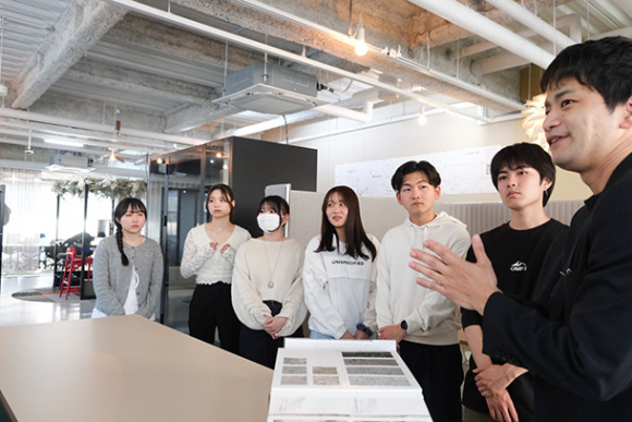 社員(右)からオフィスのこだわりについて教わる学生ら=中区の丸天産業で