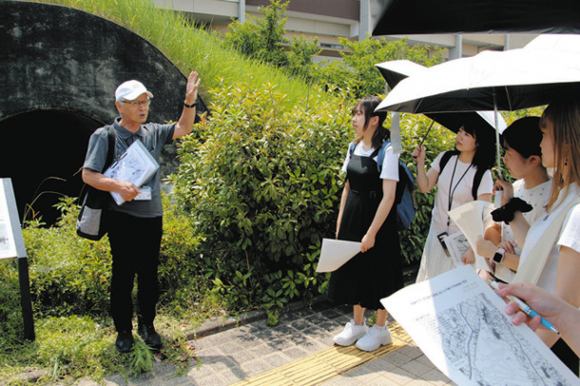 「明治航空基地」燃弾庫跡で神谷さん（左）から説明を聞く学生＝安城市東端町で