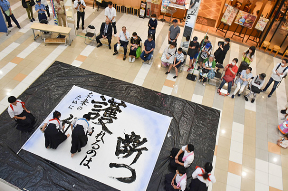 来店客を前に書道パフォーマンスを披露する部員たち=千種区千種2のイオンタウン千種で