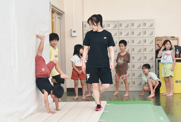 側転に挑戦する子どもたちを指導する鈴木さん(中)=日進市の愛知学院大で