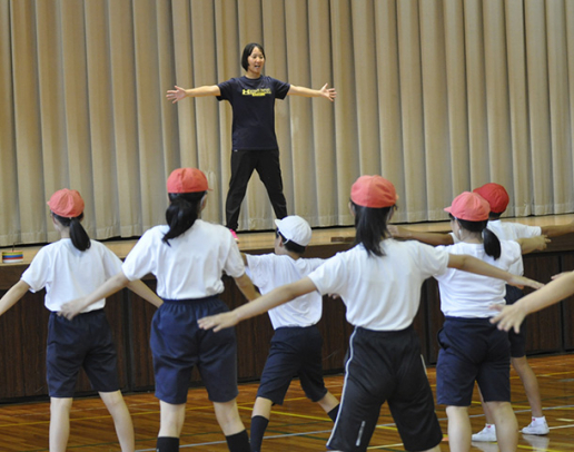 壇上の学生と「からだじゃんけん」をする児童=中津川市神坂小で