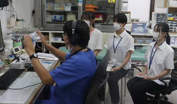 池田さん(左)が遠隔で診察する様子を見学する学生=鳥羽市桃取町の桃取診療所で