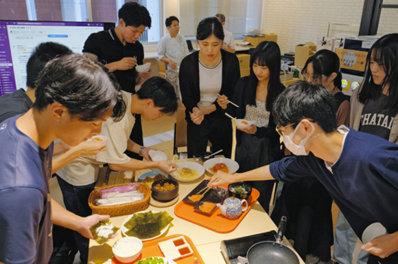 陸上養殖の「うるみえび」と「知多クールサーモン」を使った学食メニュー候補を試食する学生ら＝いずれも名古屋市昭和区の南山大で