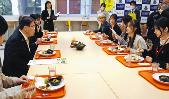 学食メニューを試食しながら大村知事（左端）と懇談する学生＝名古屋市昭和区の南山大で
