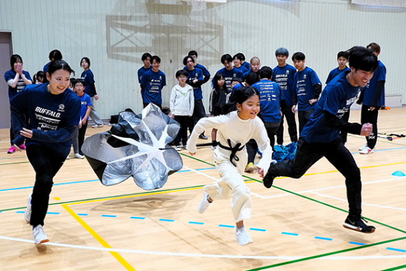 パラシュートを付けて走る練習に取り組む小学生＝春日井市の中部大で