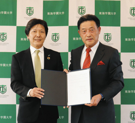 協定書を手にする石川学長（右）と井上執行役員＝みよし市福谷町の東海学園大で（東海学園大提供）
