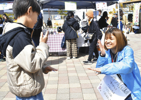 子どもに簡単な手話を教える学生(右)=長久手市勝入塚で