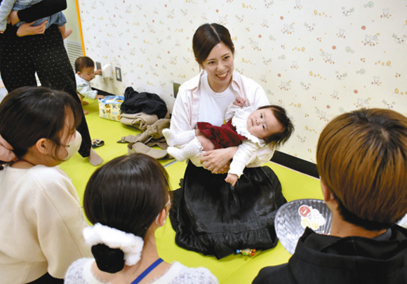 子どもをあやしながら、学生に向けて日々の育児について語る母親=名古屋市中区栄で