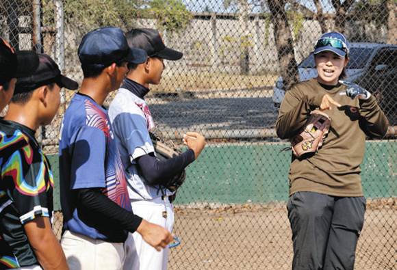 子どもたちにソフトボールを指導する佐藤はづきさん（右）＝２月２０日、タイ中部スパンブリ県で