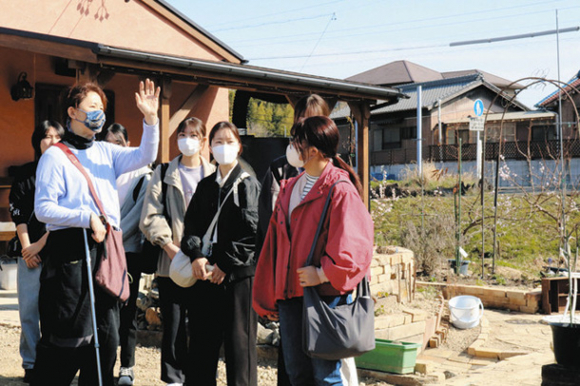 農園で育てている植物について、学生たちに説明する真柄さん（前列左）＝日進市野方町で