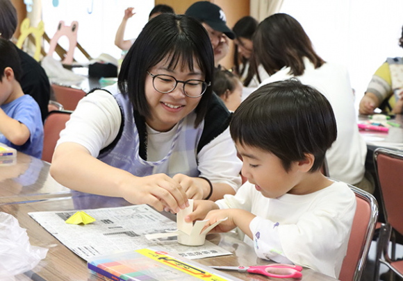 学生のサポートを受けながらコマを作る子ども＝岡崎市岡町で
