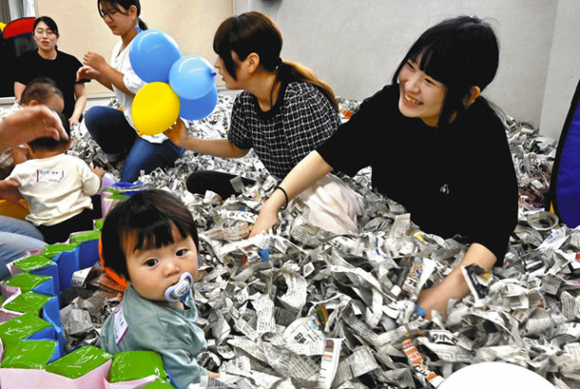 新聞プールで子どもと遊ぶ学生（右）＝津市の高田短期大で