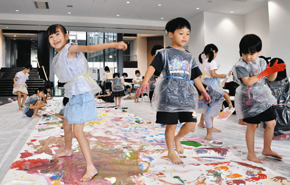 手足やスポンジなどを使って自由に絵を描く子どもら＝名東区平和が丘３の愛知東邦大で