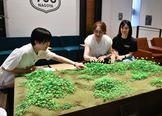 草花が生える野原を再現した牧瀬さん(左)の作品=名古屋・栄のナゴヤイノベーターズガレージで