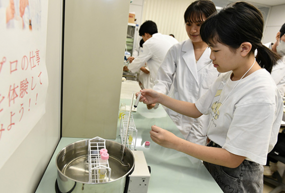 リップクリーム作りに挑戦する参加者＝鈴鹿市の鈴鹿医療科学大で
