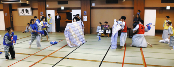 まくらを布団でガードする学生ら＝蒲郡市の旅館「平野屋」で