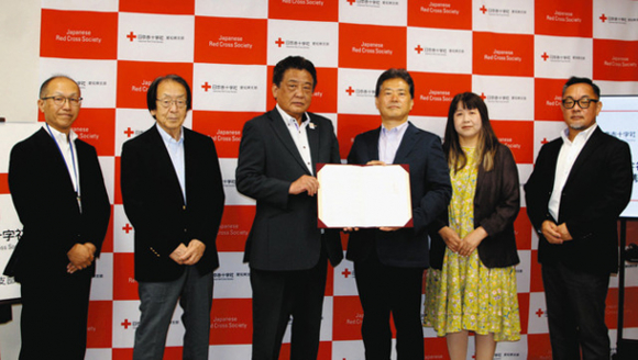 協定書を手にする中角事務局長（左から３人目）、原田学長（同４人目）＝名古屋市東区で