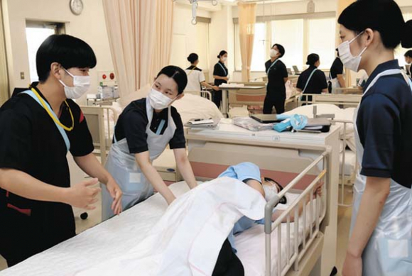 卒業生の看護師（左）から指導を受ける看護学科の学生ら＝一宮市日光町の修文大学で