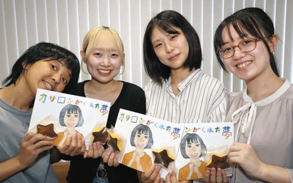制作した絵本と焼き菓子を手に活動報告する（左から）作画を担当した加藤さん、愛知大の大川さん、太田さん、小嶋さん＝中日新聞社で