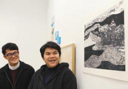 故郷の風景をイメージした作品(手前)を紹介するドゥアンケアウさん(右)=北名古屋市徳重の名古屋芸術大で